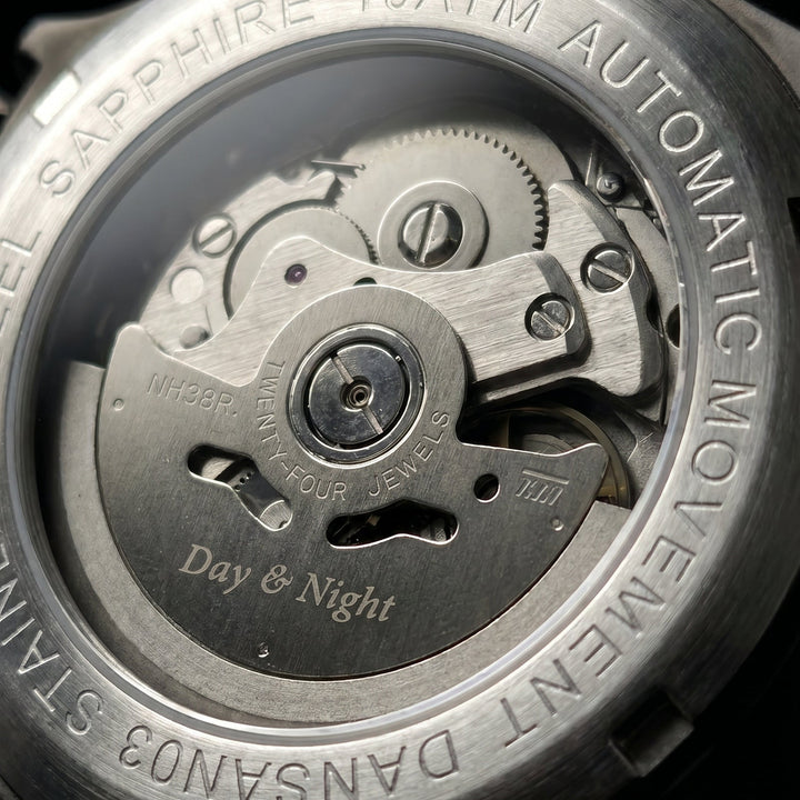 Close-up of the back case of a stainless steel automatic watch, showing the open-heart movement and sapphire crystal with engraved text 'Day & Night' and 'STAINLESS STEEL SAPPHIRE 10ATM AUTOMATIC MOVEMENT'.